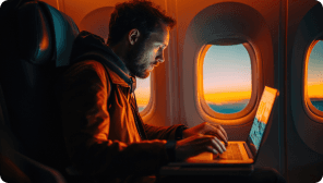 a man hunched over his laptop on a private jet
